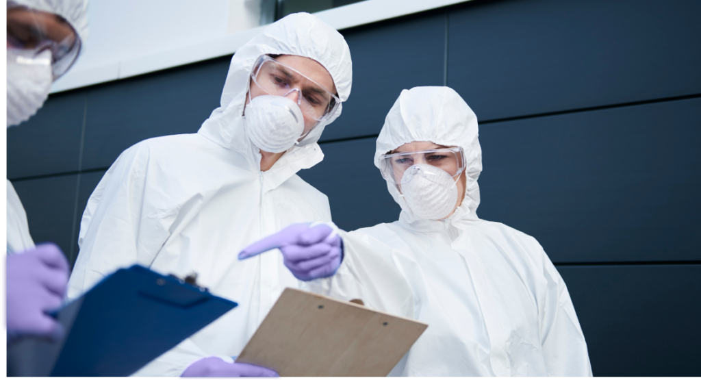 wearing hazmat suit pointing to clipboard