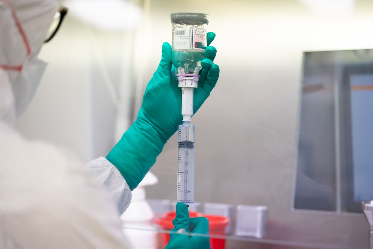 Pharmacist in a cleanroom drawing a dose from a vial into an EQUASHIELD Syringe Unit